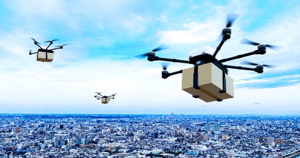 Multiple UAVs carrying delivery boxes over urban area