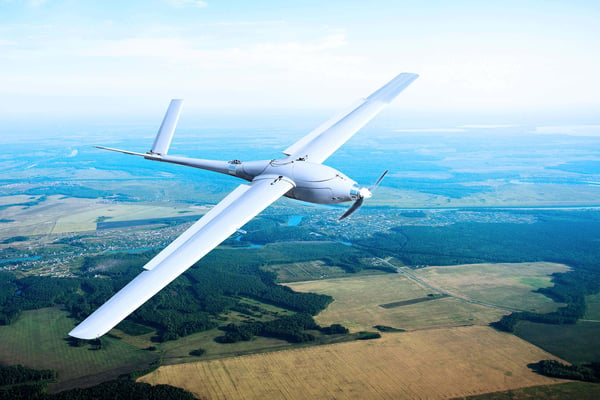 Graphic of a fixed wing drone flying over countryside